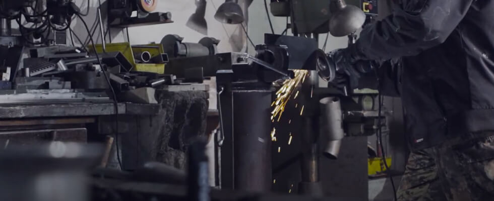 Mann der Metall mit einer Flex-Maschine bearbeitet