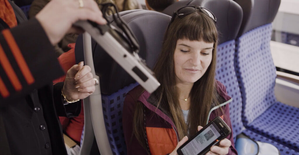 Frau in der Bahn zeigt Fahrkarte am Handy